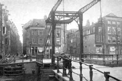 De brug over de Rapenburgerwal, links de Uilenburgerstraat, rechts de Batavierstraat. Het blok huizen tussen die straten is verwijderd. De ruimte die toen ontstond werd gebruikt voor de Nieuwe Uilenburgerstraat, en is ook de reden dat er voor de Uilenburgersjoel een voorplein is. De pakhuizen links in de Uilenburgerstraat staan er nog. 